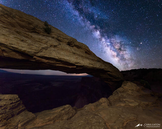 The center of the Milky Way galaxy rises above Mesa Arch in Canyonlands National Park. Deep in the distant dark is the White Rim above the Colorado River.