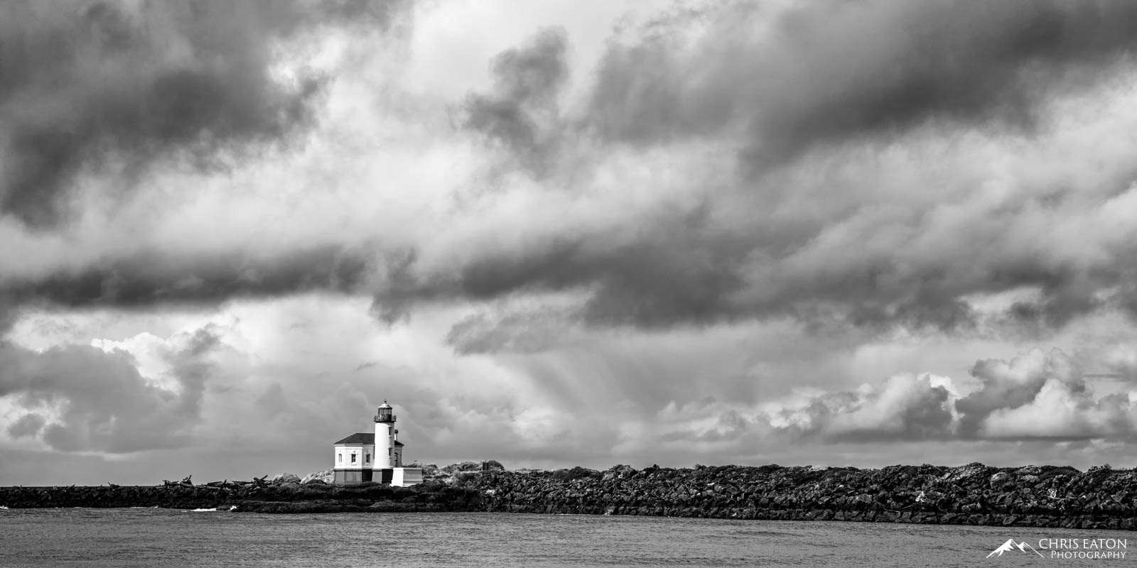 A winter storm rolls in from the Pacific Ocean and the Coquille River Lighthouse stands guard over the rocky Oregon coast of...