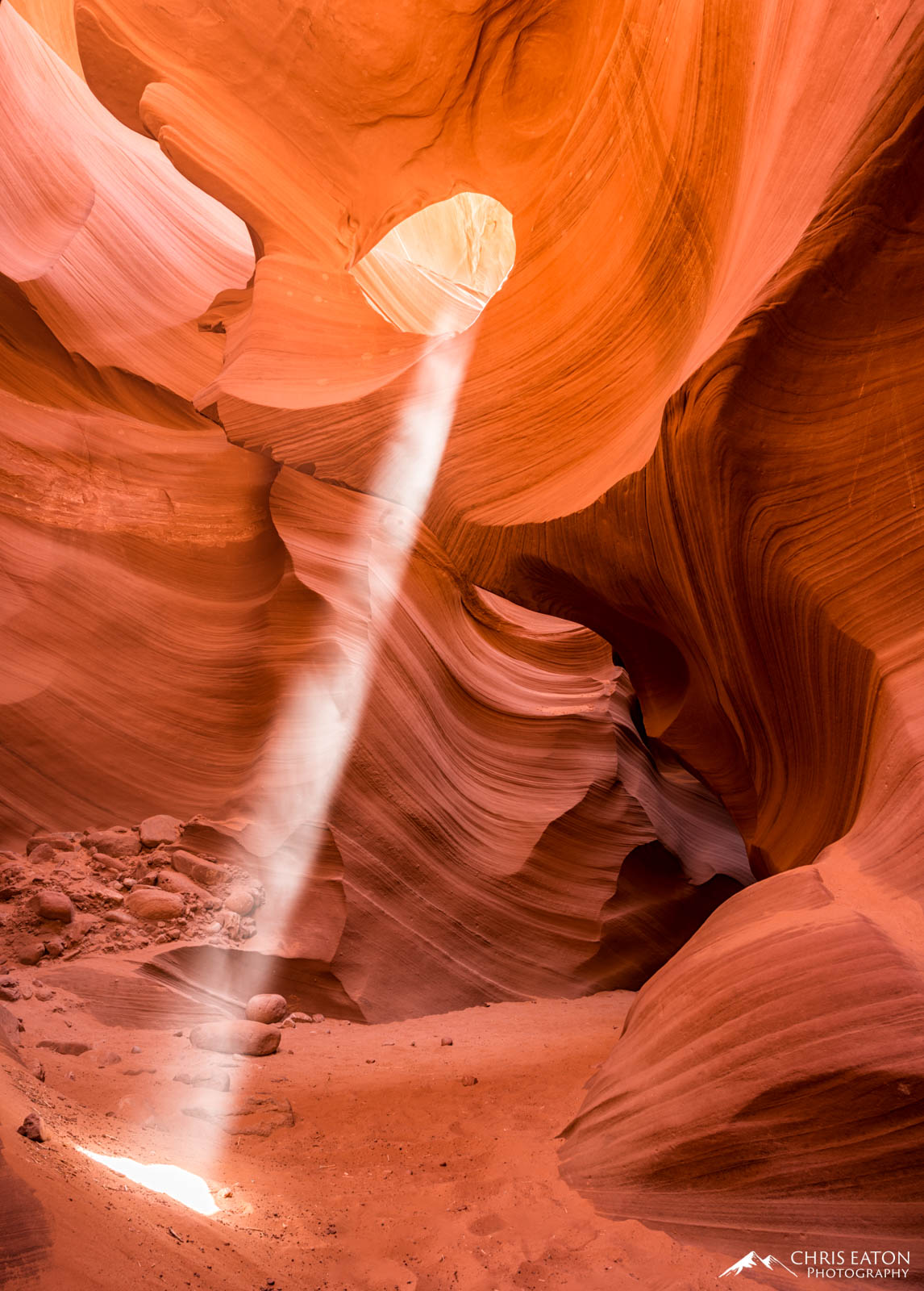 Deep in the center of Lower Antelope Canyon a hanging arch is carved through a fin of Navajo Sandstone. Mid-morning, a shaft...