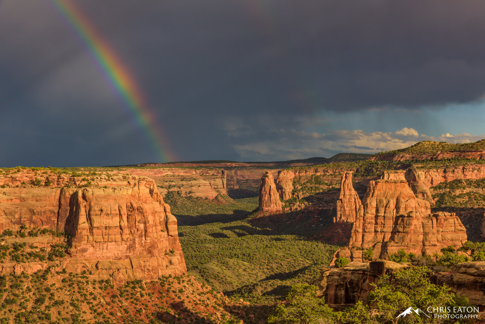 The end of the rainbow reaches to Monument Canyon in Colorado National Monument as the sun begins to set on the remnants of a...