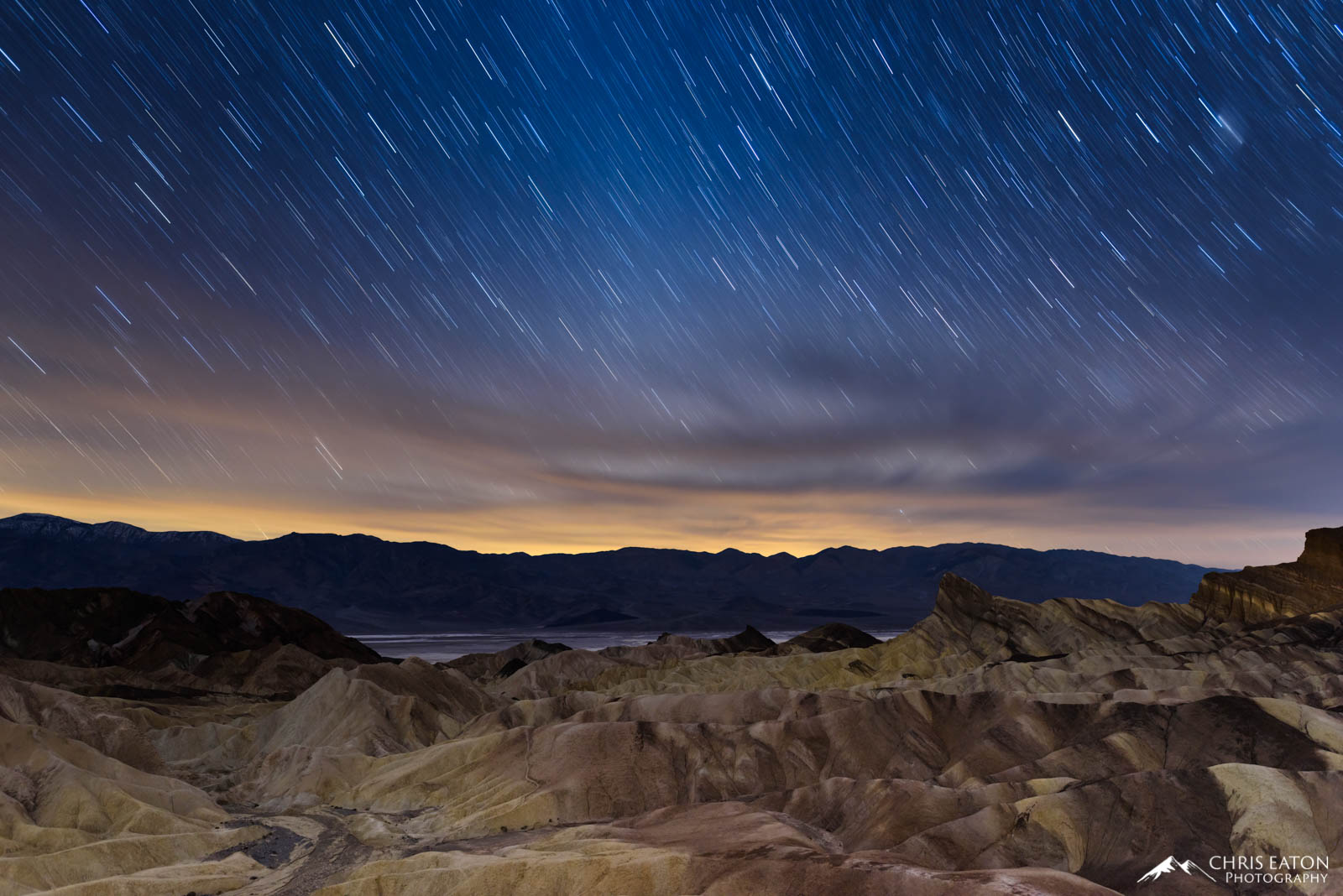 Star trails over Manly Beacon at Zabriskie Point in Death Valley National Park.