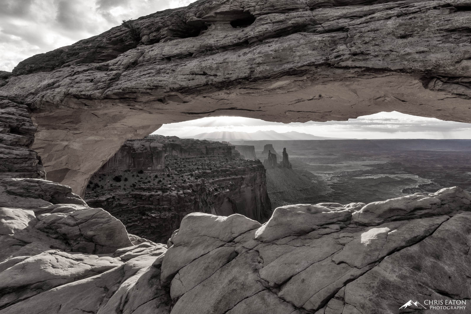 Mesa Arch frames a window on the Canyonlands of the White Rim. Mesa Arch is a pothole arch formed when a regular pool of surface...