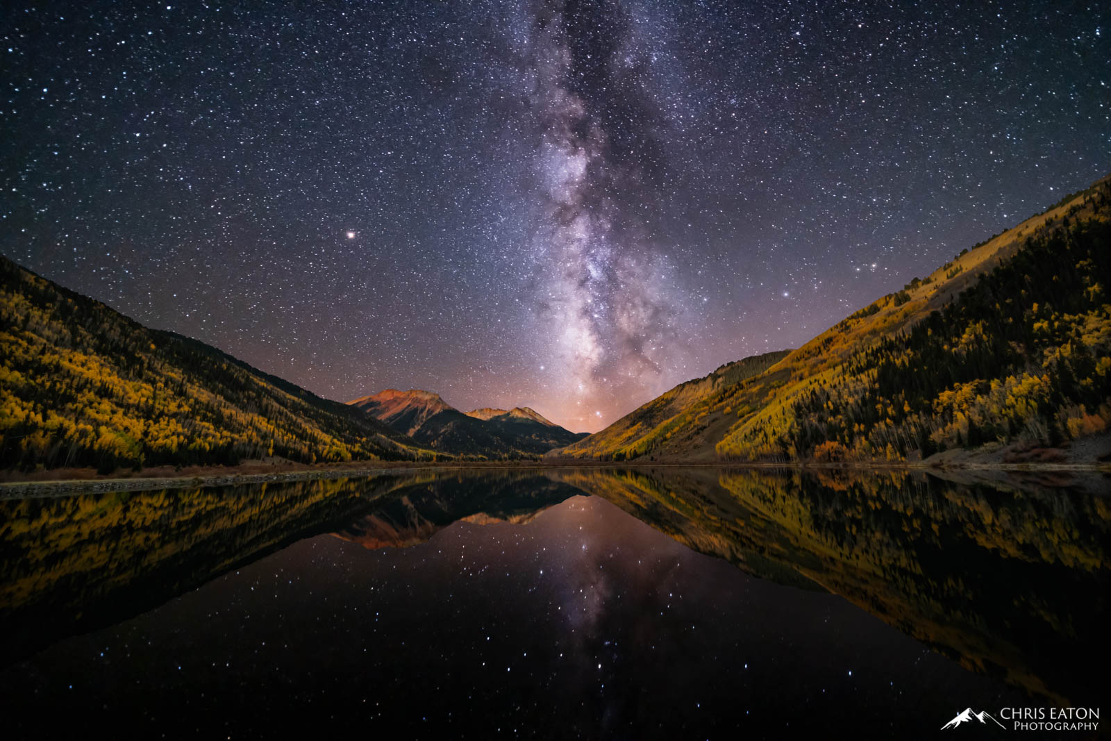 The Milky Way galaxy rises above Crystal Lake and fall color aspen trees in the San Juan Mountains of Colorado.