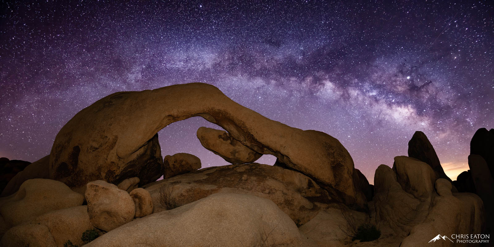 The early morning Milky Way rises above Arch Rock in the White Tank area of Joshua Tree National Park.